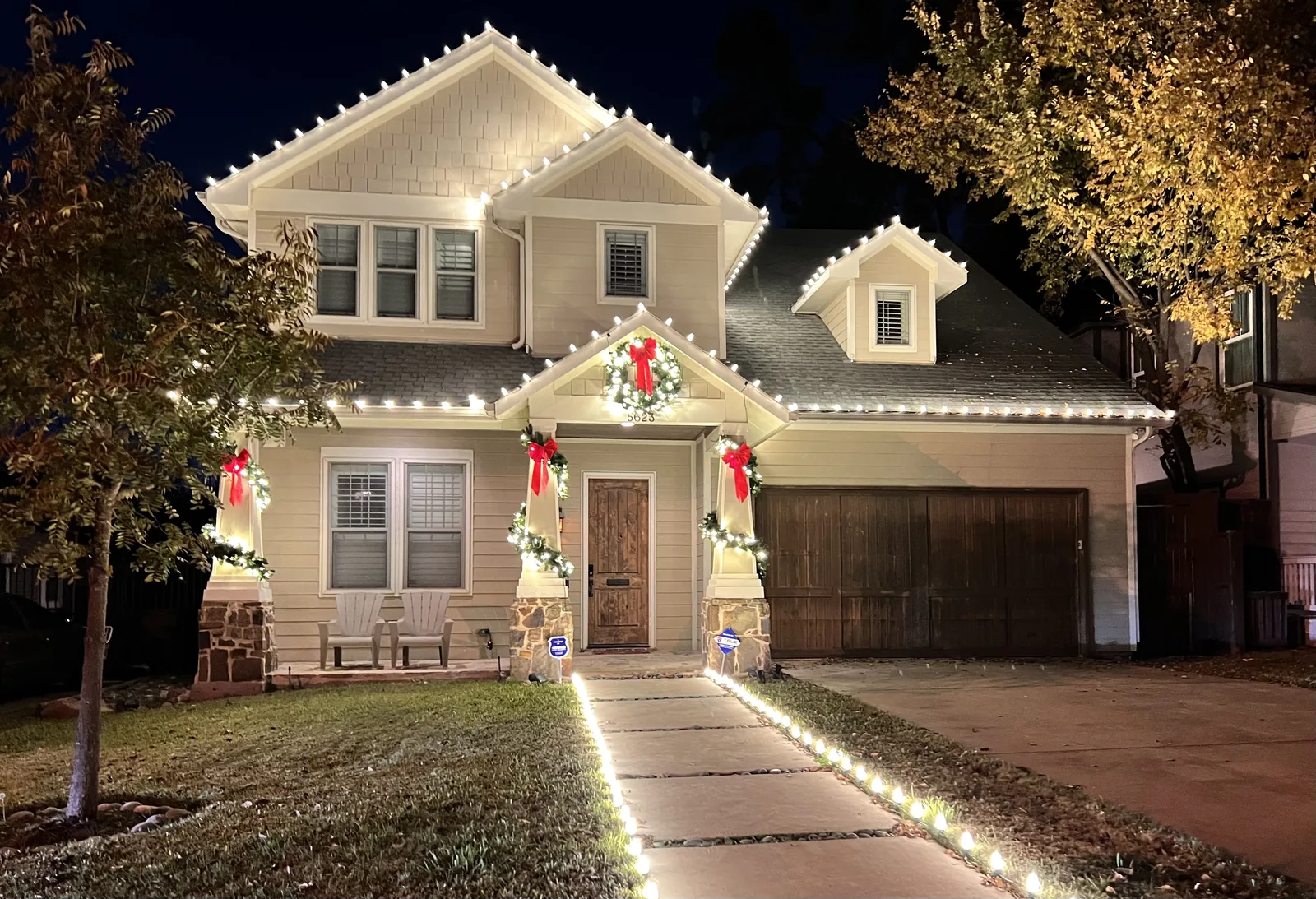 Christmas light installation Flower Mound TX — warm white roofline, lit garland and wreaths on a family home
