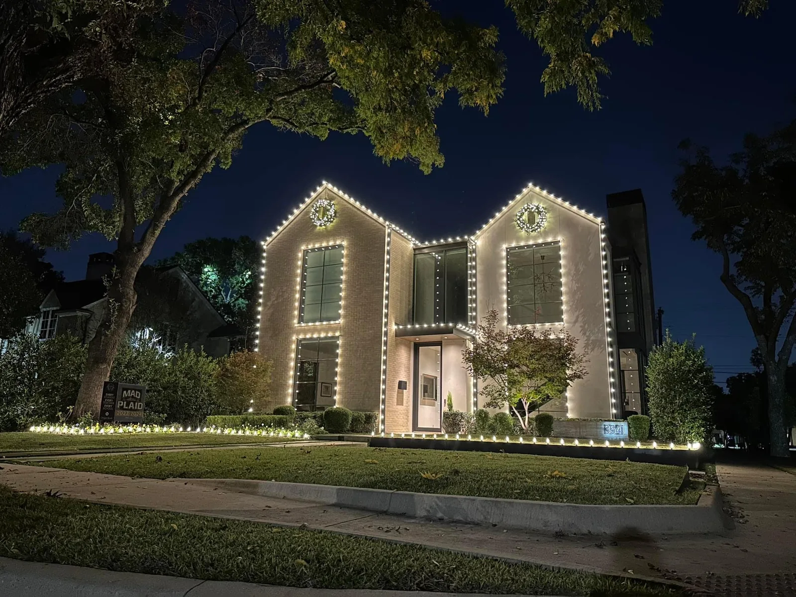 Christmas light installation Dallas TX — warm white roofline and lit wreaths on a modern transitional home