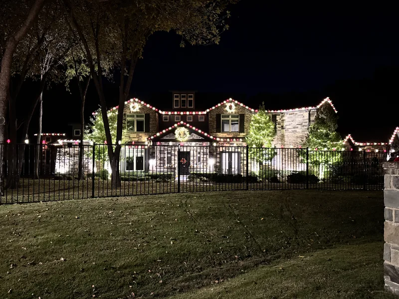 Christmas light installation Carrollton TX — red and white roofline lighting on a two-story brick home