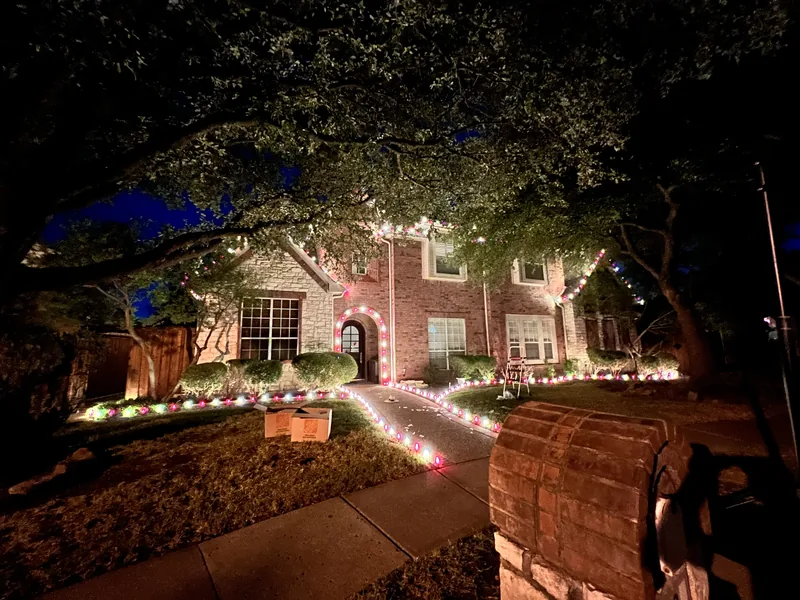 Christmas light installation Coppell TX — multicolor roofline and path lighting on a brick home