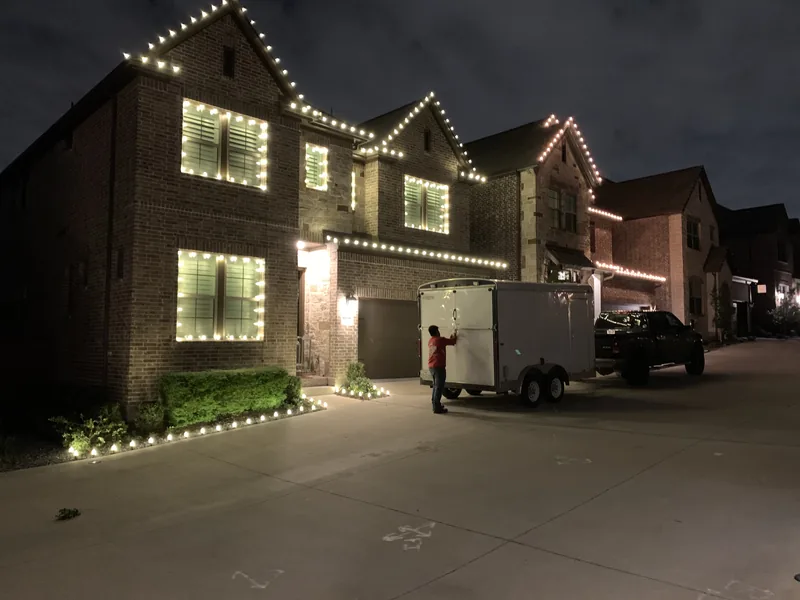 Christmas light installation Dallas TX — crew installing tree wrapping on a luxury home