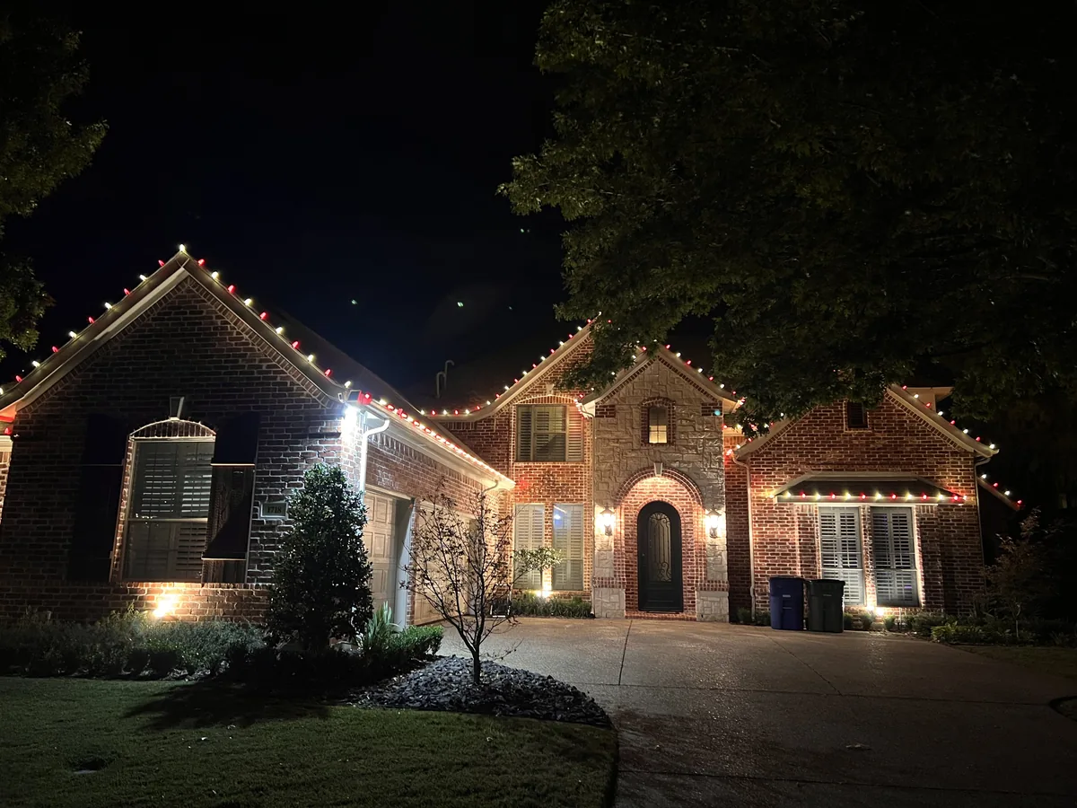 Christmas light installation Garland TX — warm white roofline and landscape lighting on a brick estate