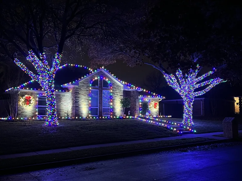 Christmas light installation Garland TX — red and green roofline lighting on a two-story brick home