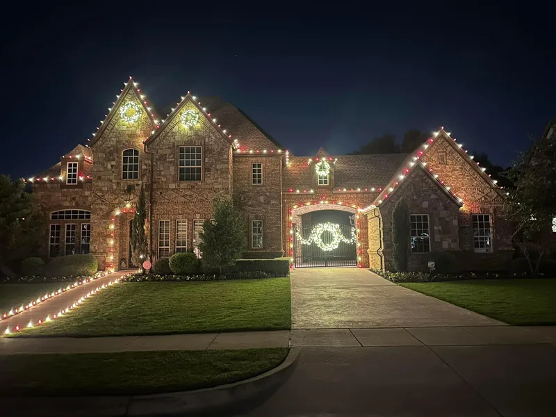 Christmas light installation Garland TX — warm white roofline outlining the gables of a stone home