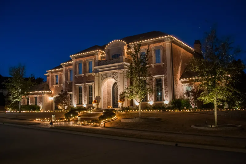 Christmas light installation Grapevine TX — warm white roofline and landscape lighting on a brick estate