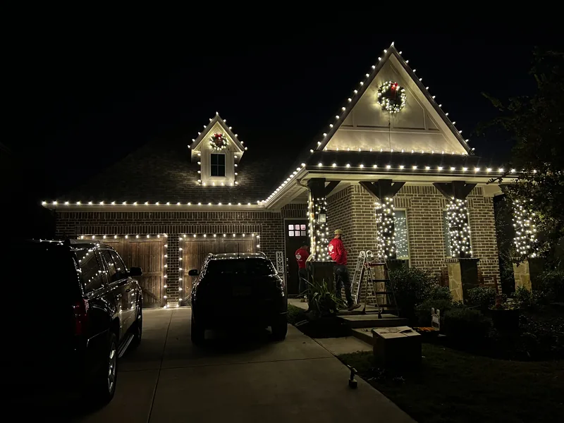 Christmas light installation McKinney TX — warm white roofline and wreaths on a brick home