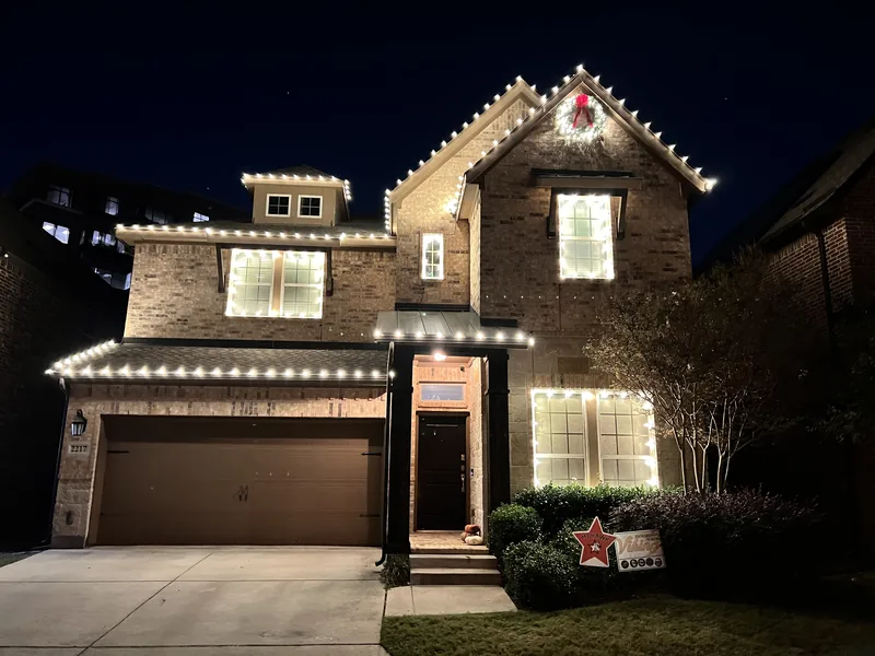 Christmas light installation Richardson TX — warm white roofline and wreath on a two-story brick home