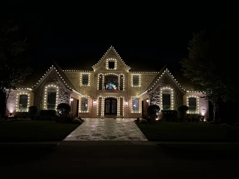 Christmas light installation Rockwall TX — warm white roofline outlining the gables of a stone home