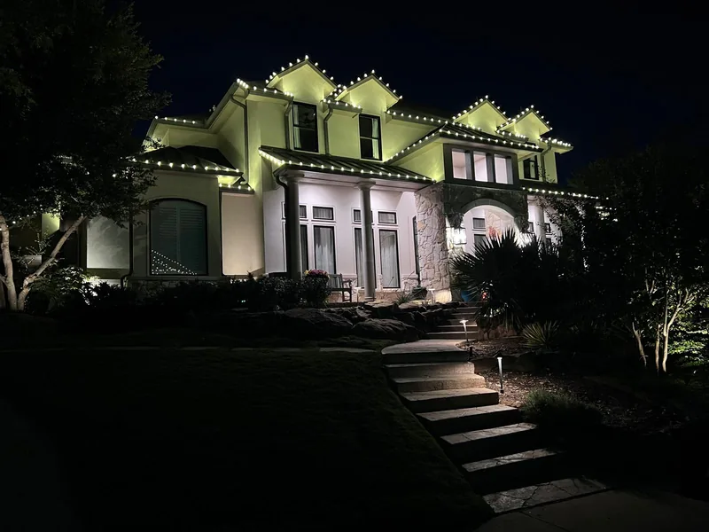 Christmas light installation Stonebriar Country Club TX — warm white roofline and uplit entry on a stucco estate