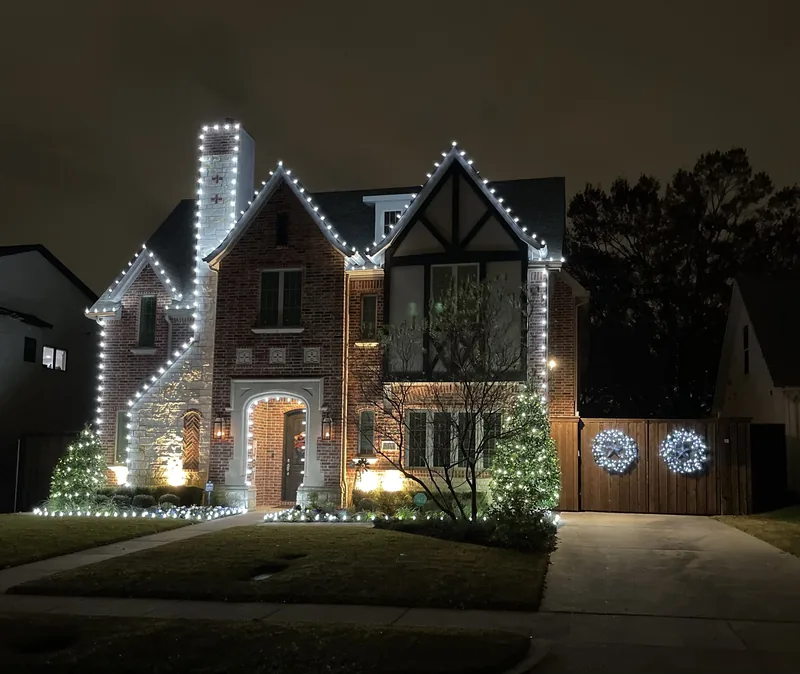 Christmas light installation Vaquero Club TX — warm white roofline and lit wreaths on a brick Tudor home