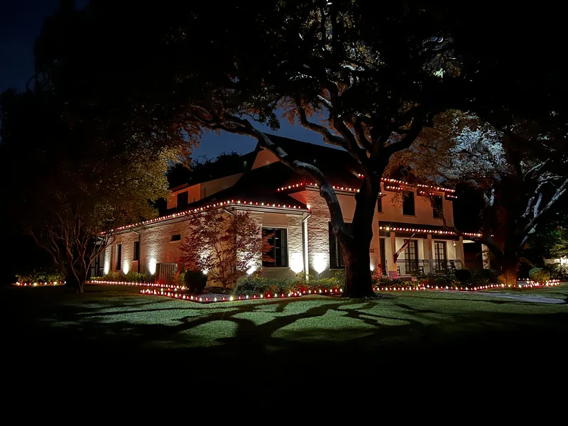 Christmas light installation Volk Estates TX — warm white roofline and landscape lighting on a brick estate